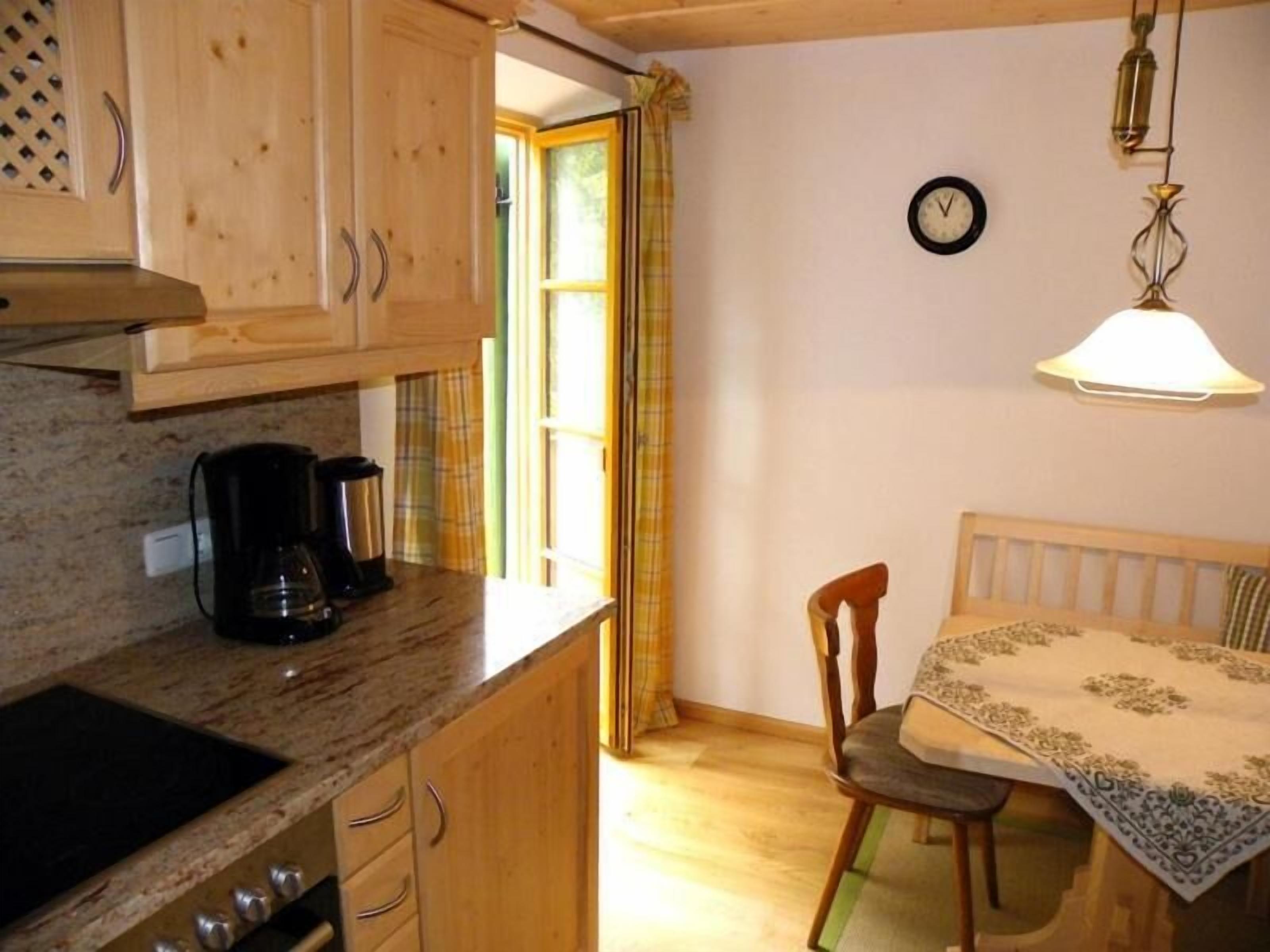 A kitchen with wooden cabinets, a coffee maker, and a dining area with a table and chairs.