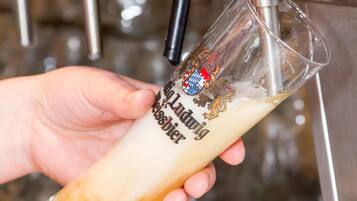 Eine Hand hält ein Glas mit einem Logo und Text, das unter einem Wasserhahn platziert ist.