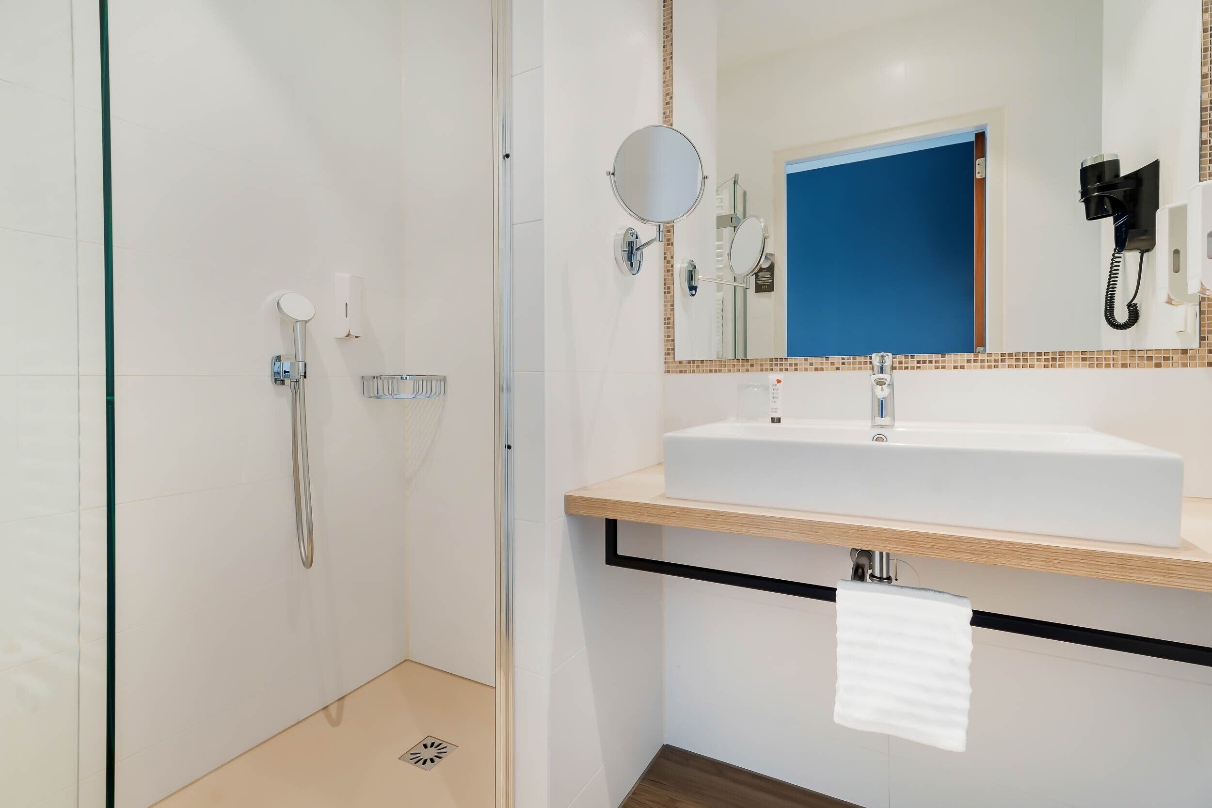 Un baño moderno con ducha, lavamanos y espejo.