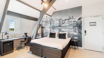 Un dormitorio moderno con cama, escritorio y silla, con un mural de paisaje urbano en la pared.