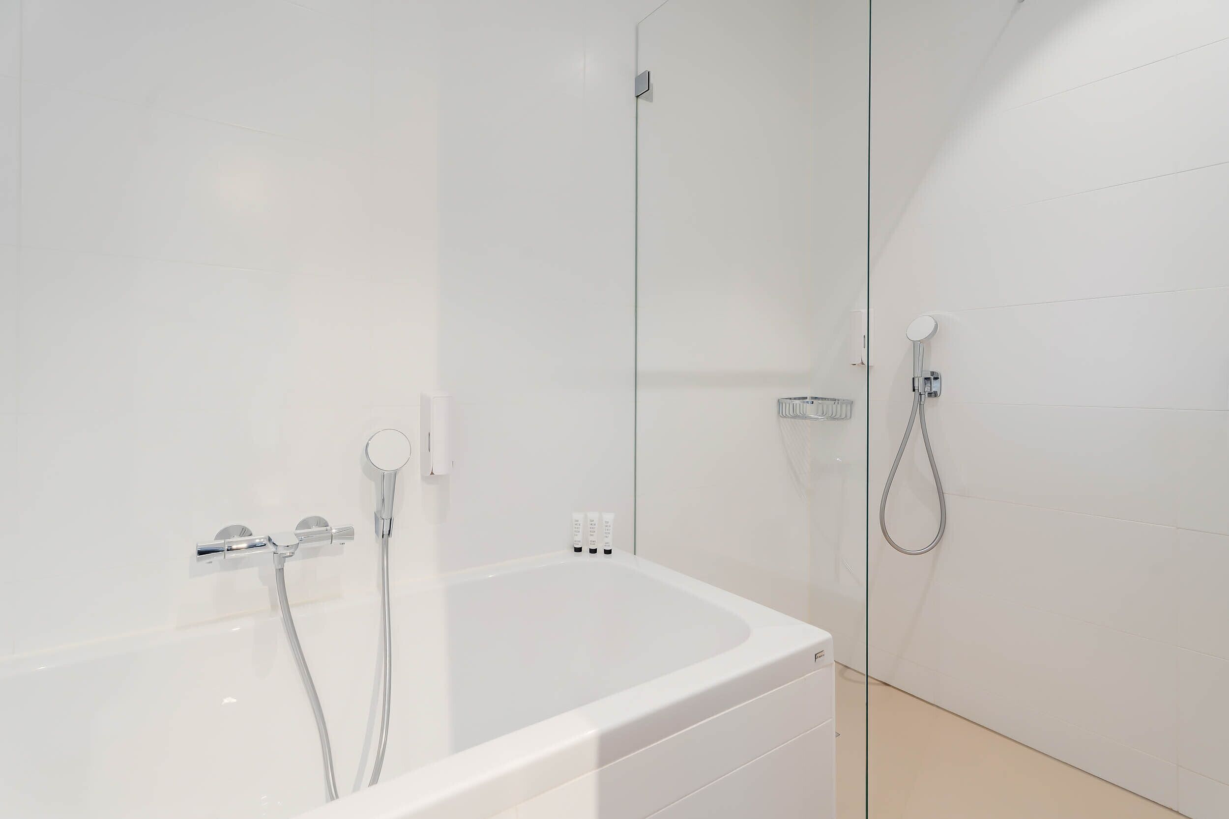 Een moderne badkamer met een witte badkuip, een douchecabine met glazen wanden en chroombeslag.