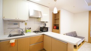 Une cuisine de taille réduite, équipée d’un évier, d’une cuisinière, d’un four à micro-ondes et de meubles de rangement en bois.