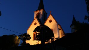 A church with a tall steeple and a clock tower, illuminated at dusk.