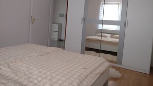 Ein Schlafzimmer mit einem Bett, einem Kleiderschrank mit Spiegel und einem kleinen Schreibtisch.