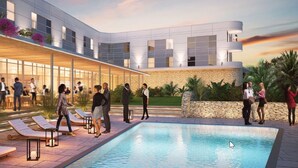 A modern hotel with a swimming pool, outdoor seating, and a covered patio area.