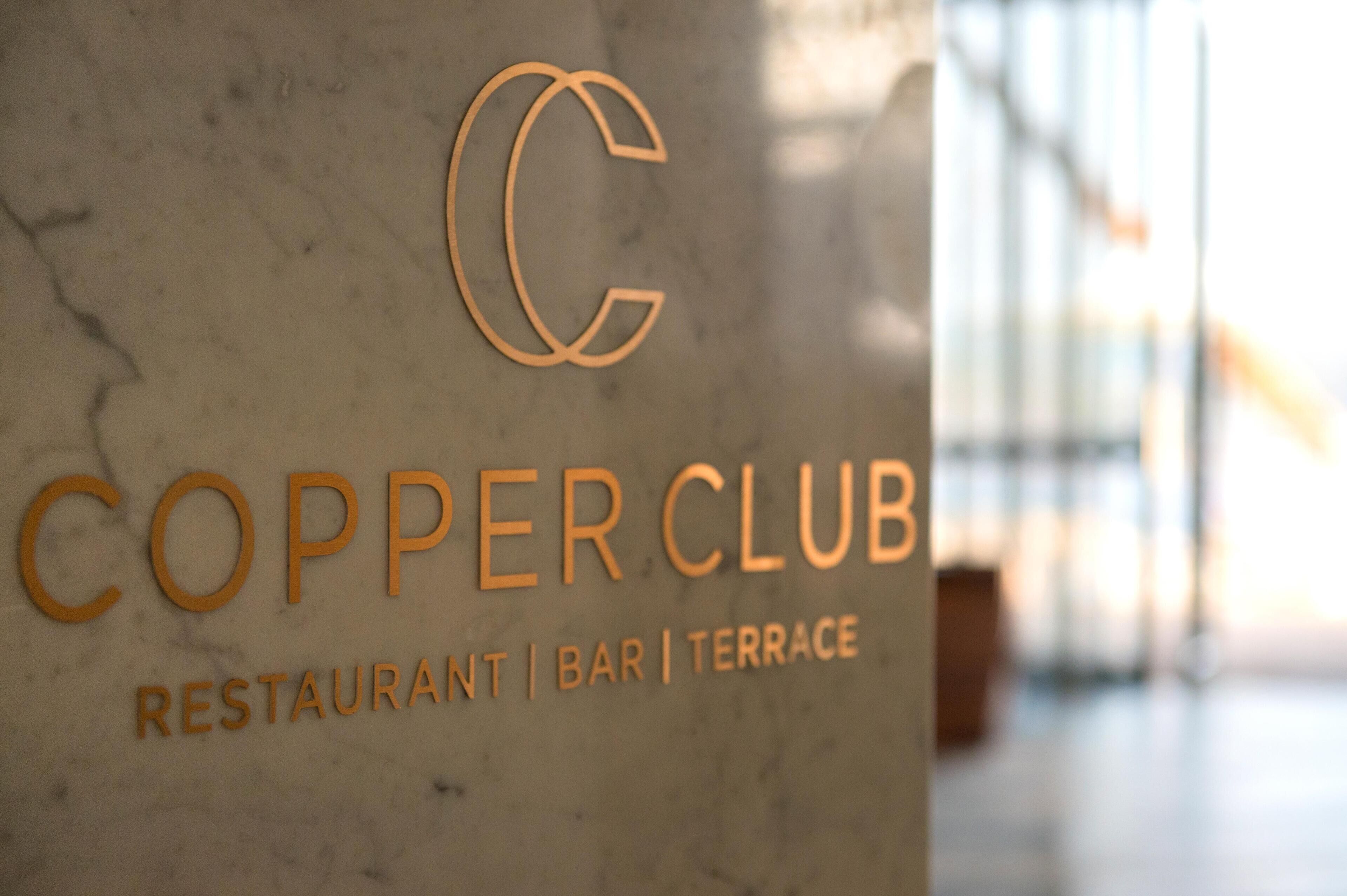 A marble wall with the text "COPPER CLUB" and "RESTAURANT | BAR | TERRACE" indicating the establishment's name and services.