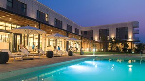 Um hotel moderno com área de piscina, espreguiçadeiras e guarda-sóis.