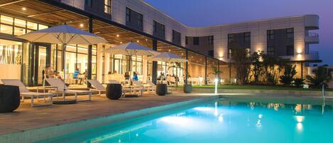 Una piscina al aire libre, sillones reclinables de piscina