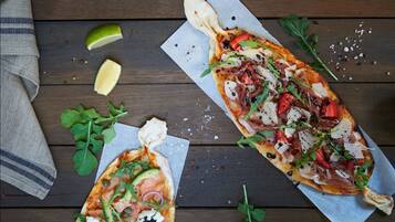 Dos pizzas sobre tablas de madera con distintos ingredientes y media lima.