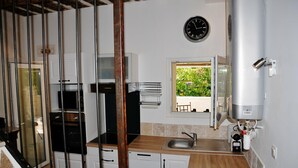 A modern kitchen with a built-in oven, a dishwasher, and a window with a view of greenery. - Au Mazet de Carmélina, an old building dating from 1850 in the heart of the Alpilles mountains (Paradou)