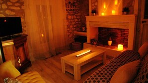 A cozy living room with a stone wall, a fireplace, a wooden coffee table, and a patterned sofa. - Au Mazet de Carmélina, an old building dating from 1850 in the heart of the Alpilles mountains (Paradou)