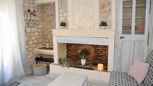 A cozy living room with a fireplace, stone walls, and a door with glass panels. - Au Mazet de Carmélina, an old building dating from 1850 in the heart of the Alpilles mountains (Paradou)