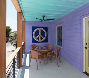 Relax under the ceiling fan in this serene outdoor space, featuring a round table and wicker chairs.