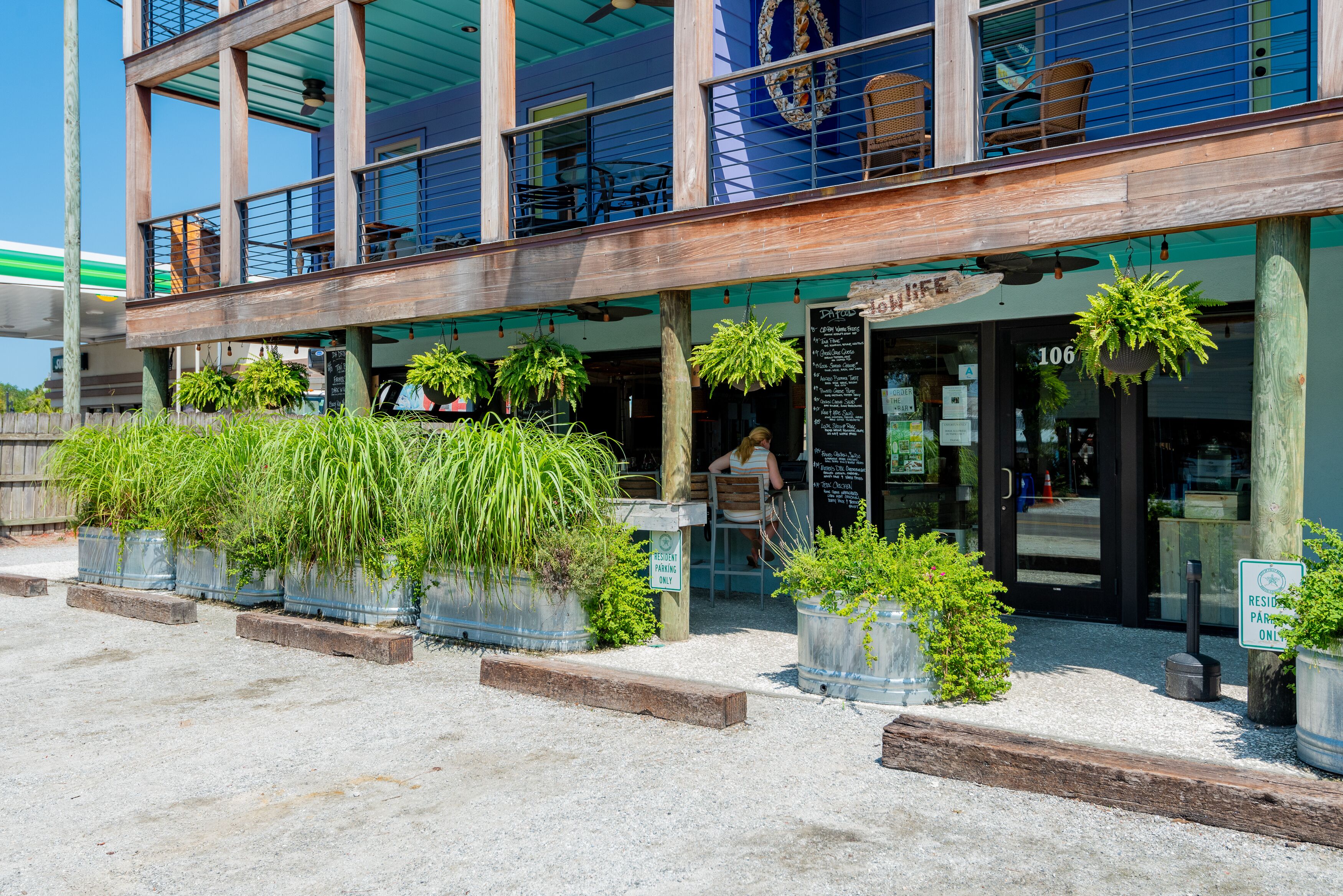 Un edificio con fachada de madera, mesas al aire libre y plantas en macetas.