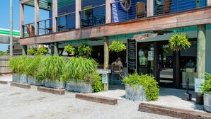 A building with a wooden facade, outdoor seating, and potted plants.