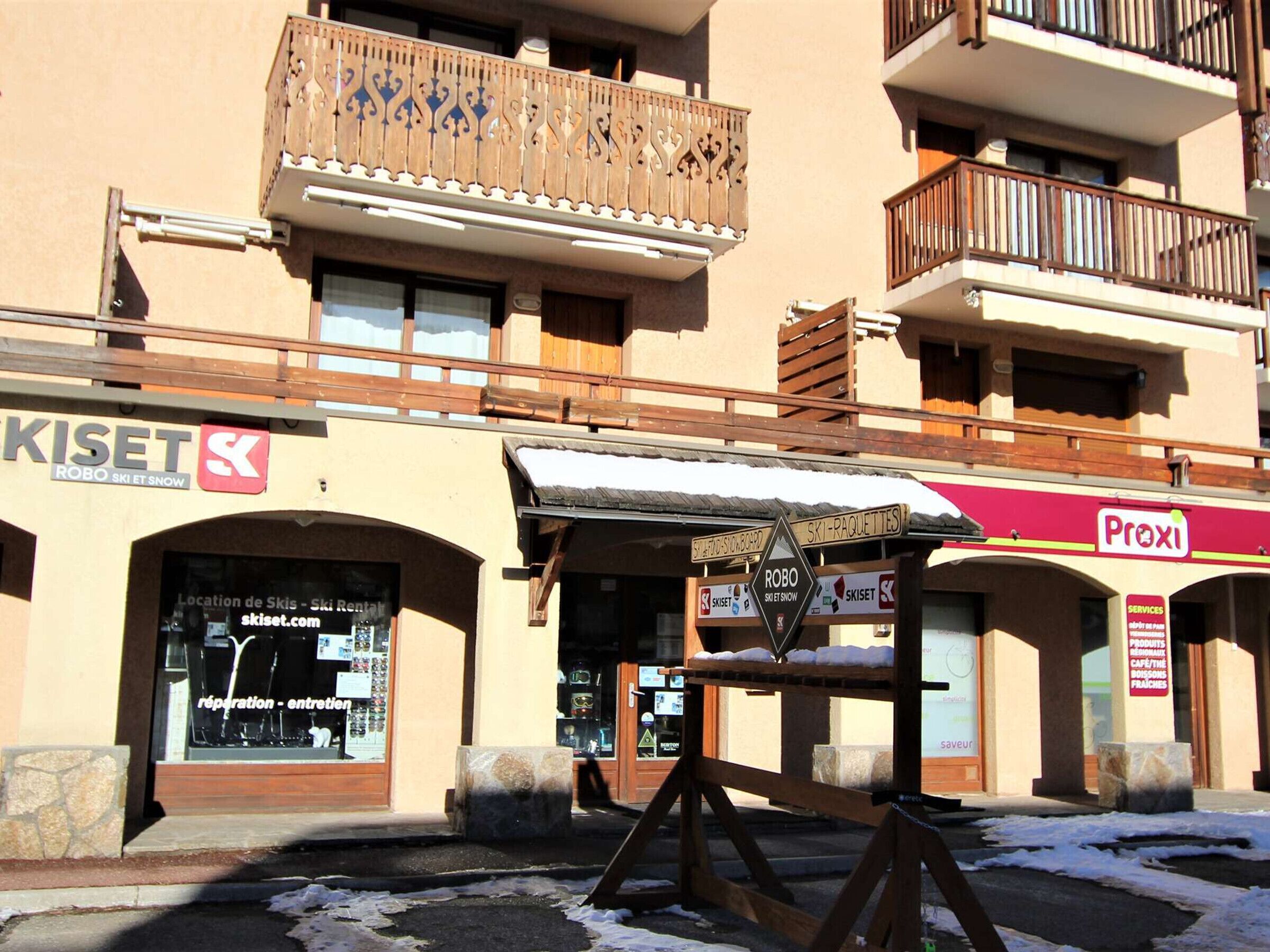 Un immeuble abritant plusieurs commerces, notamment un magasin de location de matériel de ski et un café.