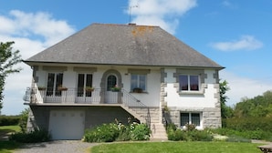 A two-story house with a balcony, a garage, and a stone facade.