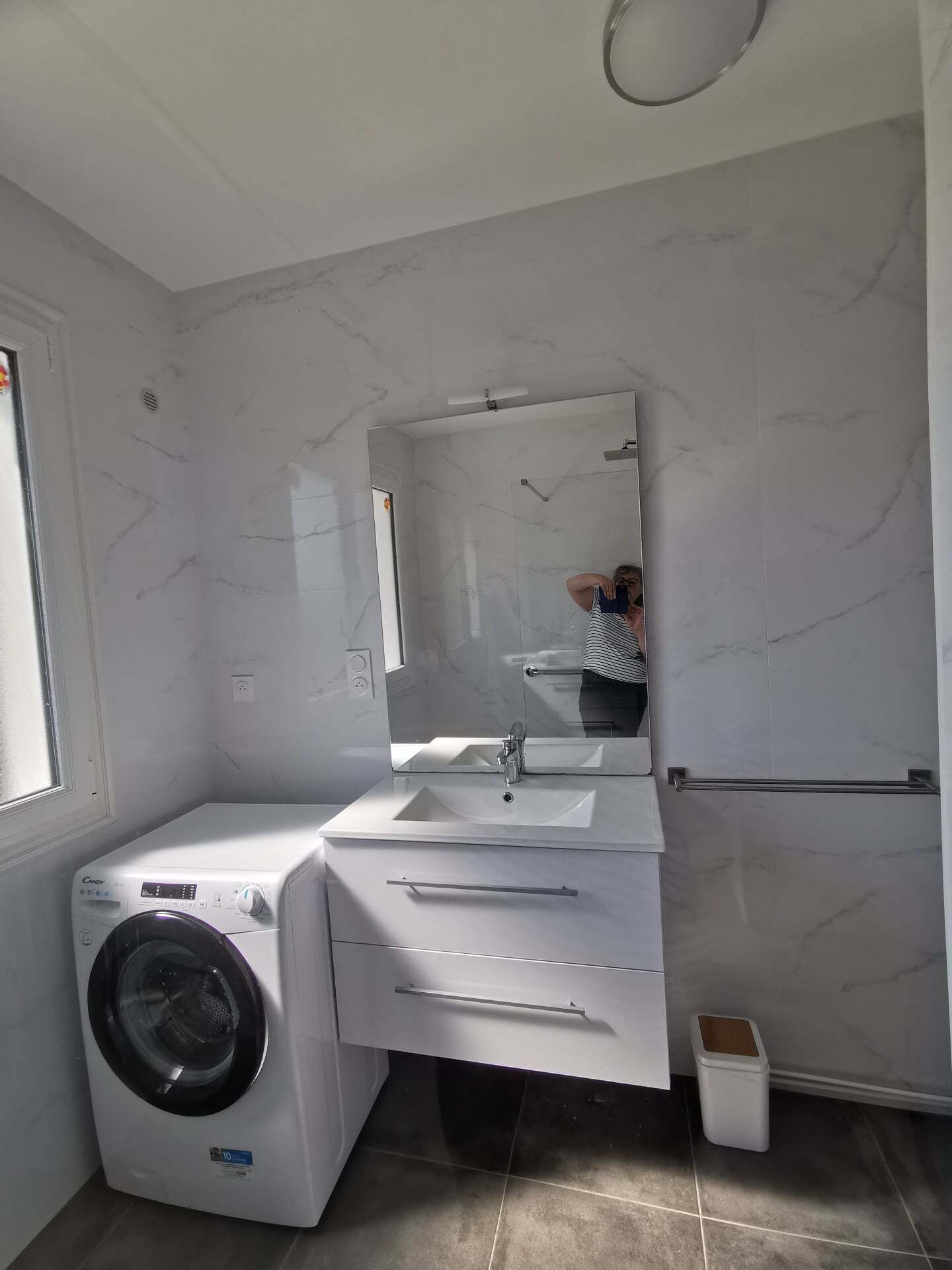Uma casa de banho moderna com máquina de lavar embutida, lavatório e espelho.