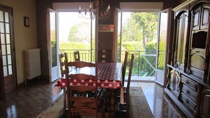 A dining area with a table set for four, a chandelier, and a view of a garden through a glass door.