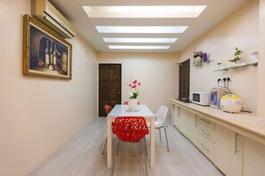 A compact kitchen with a dining area, featuring a table with chairs, a microwave, and a small refrigerator. - Botanic Elegant Suite Klang (Pelabuhan Klang)