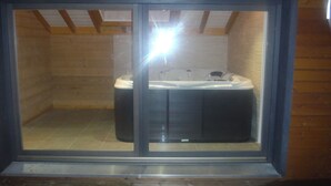 A hot tub in a wooden room with a glass enclosure.