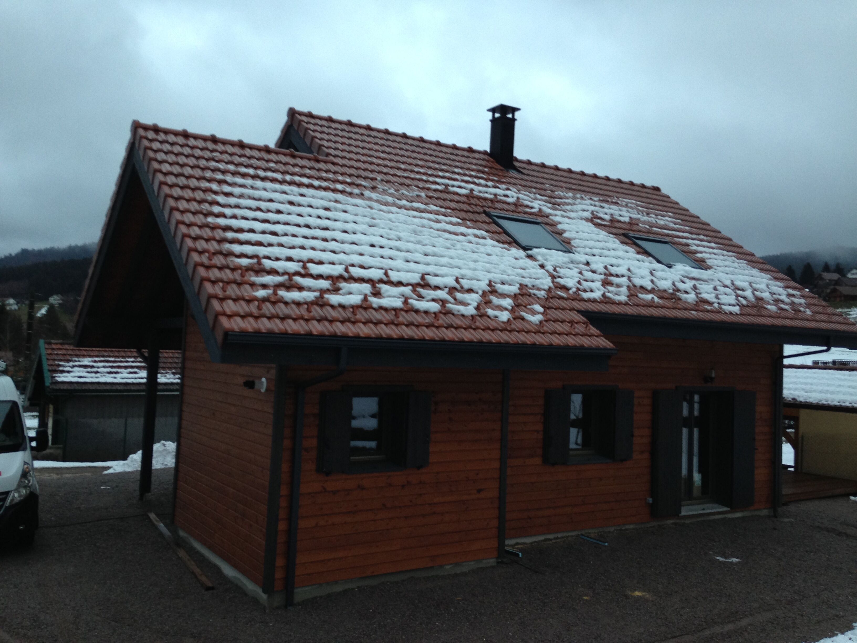 Un petit bâtiment en bois, doté d’un toit en pente recouvert de neige, avec deux fenêtres et une porte.