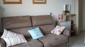 Een bruine bank met gekleurde kussens en een klein wit kastje met spiegel en decoratieve voorwerpen.