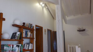 Une pièce spacieuse avec des étagères en bois remplies de livres, un radiateur blanc et une petite maquette de bateau accrochée au mur.