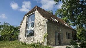 Une maison en pierre avec une grande fenêtre, un toit en pente et un petit porche.