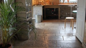 Une cuisine rustique avec un sol en pierre, un plafond en bois et un mur en pierre.