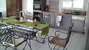 Une cuisine moderne avec un coin repas, comprenant une table avec des chaises, un four à micro-ondes, un four et un évier.