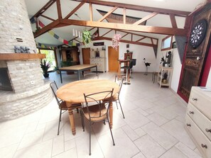Un coin repas rustique avec un mur en pierre, des poutres en bois, une table ronde et des chaises.