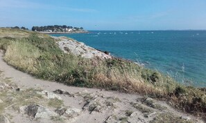 Um caminho costeiro com terreno rochoso e vista para o mar.