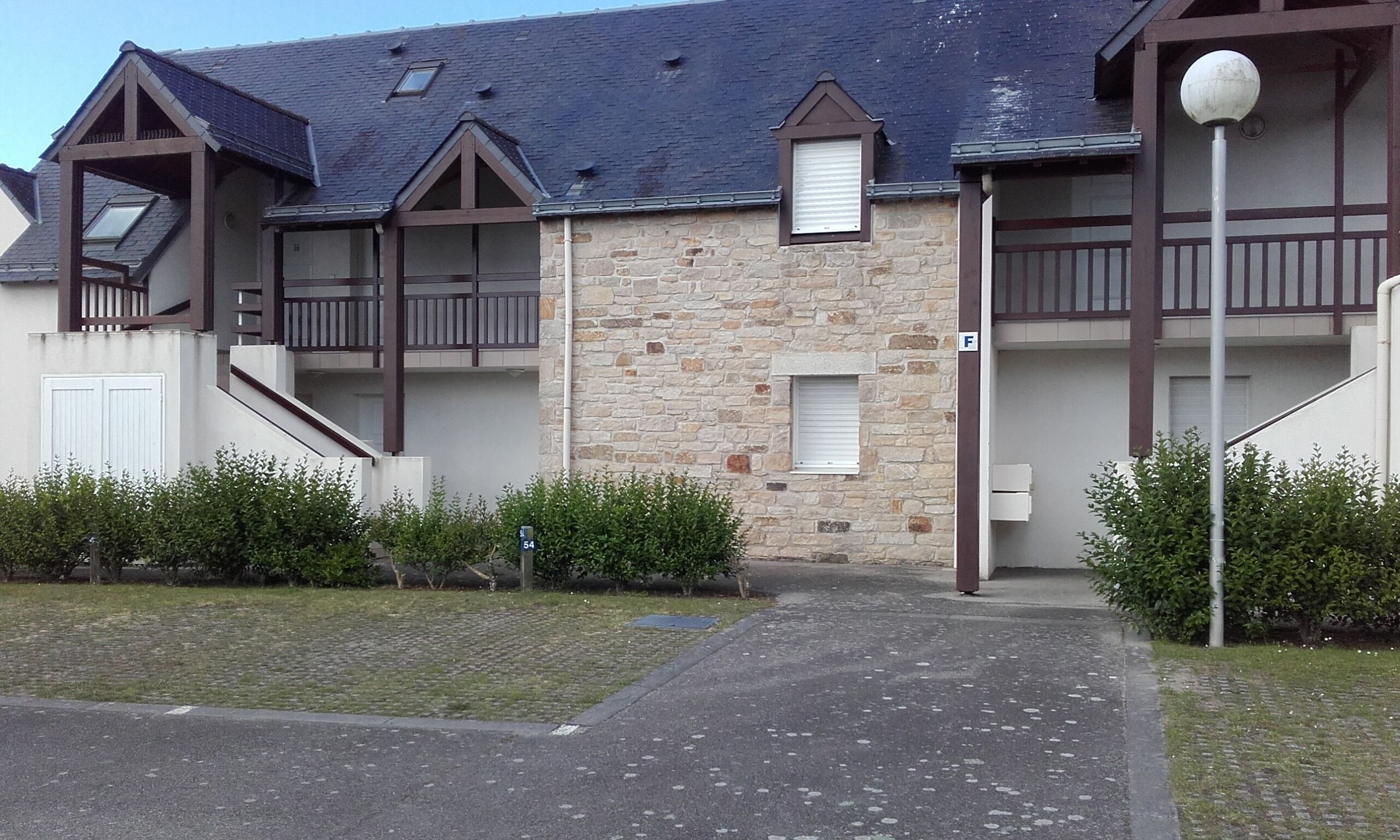 Un immeuble à plusieurs étages, doté d’une façade en pierre, de balcons et d’une entrée couverte.
