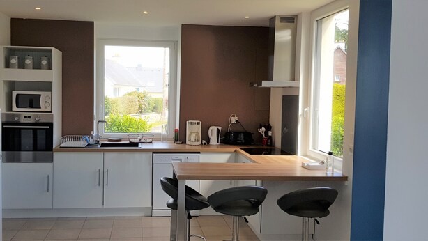 A compact kitchen with white cabinets, a microwave, a stove, and a coffee maker. There is a window providing a view of the outside.