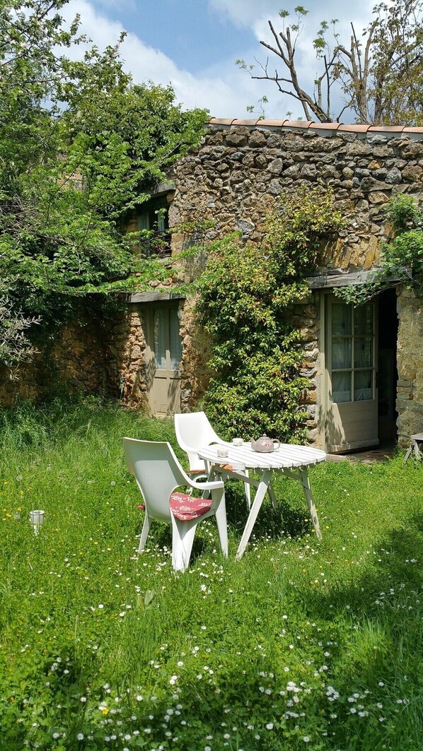 A stone building with a small garden area featuring a table and chairs.