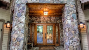 A stone-clad entrance with a wooden door and a stone-paved entrance area.