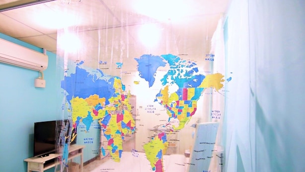 Una habitación con un gran mapa mundial en la pared, un televisor y una mesita.