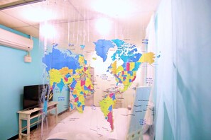 A room with a large world map on the wall, a television, and a small table. - Starry Shennong (Tainan)