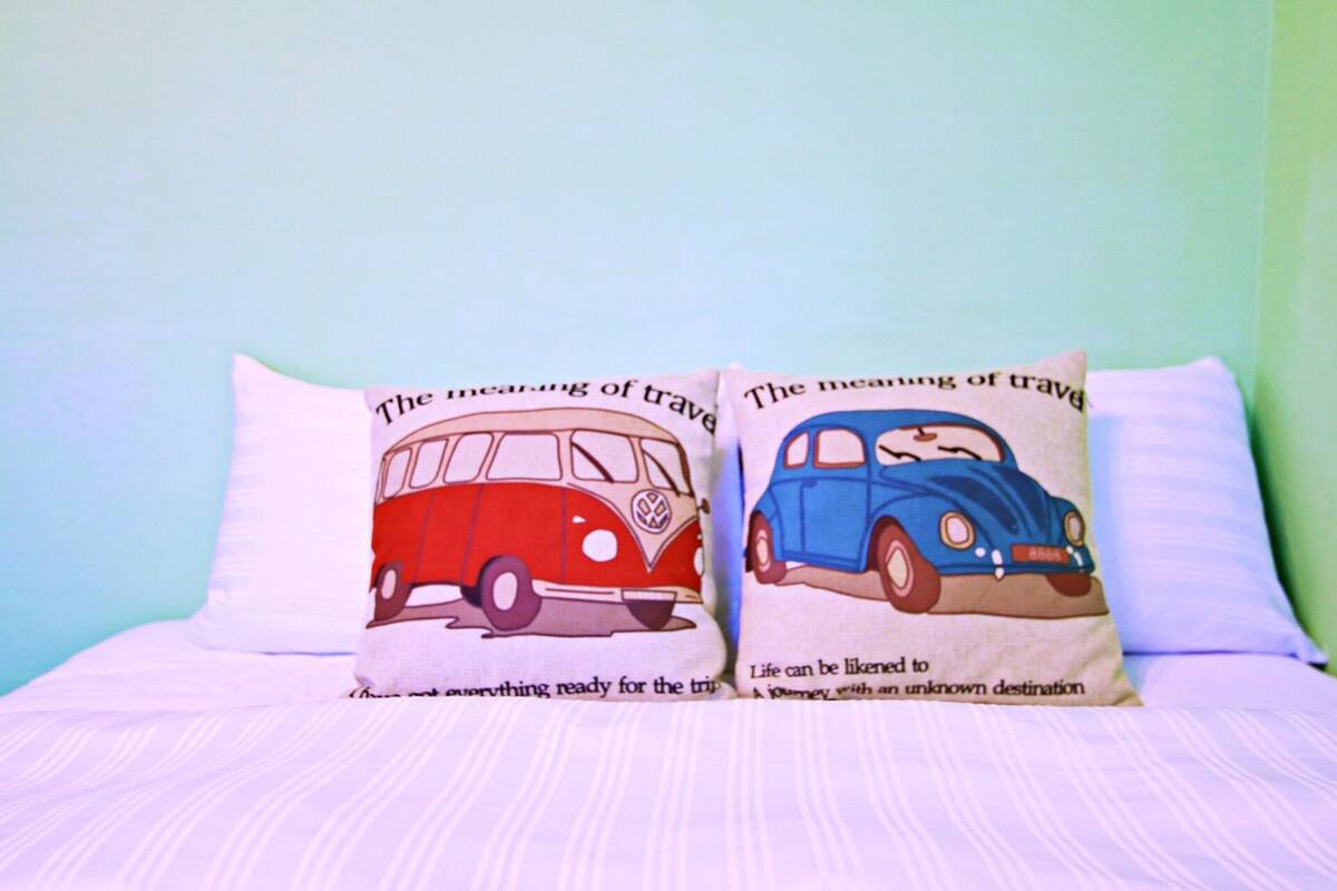 Dos almohadas con diseños de viajes sobre una cama.