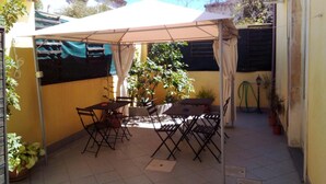 A patio with a table and chairs under a canopy, surrounded by potted plants and a tiled floor. - B&b Scirocco d'Africa (Catania)