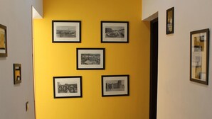 A hallway with a yellow wall and framed pictures. - B&b Scirocco d'Africa (Catania)