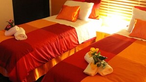 A hotel room with two beds, each with red bedding and white pillows. There are towels on the beds and a window with blinds. - B&b Scirocco d'Africa (Catania)