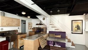 A modern kitchen with a central island, wooden cabinets, and a dining area with a bench.