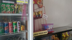 A refrigerated display case with various food items and beverages, including cans of Milo, 7up, and Red Bull, as well as shelves stocked with Nescafe and other products. - Daddy's Inn (Lumut)
