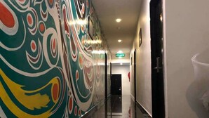 A hallway with a colorful mural on the left wall, a clean floor, and a door at the end. - Daddy's Inn (Lumut)