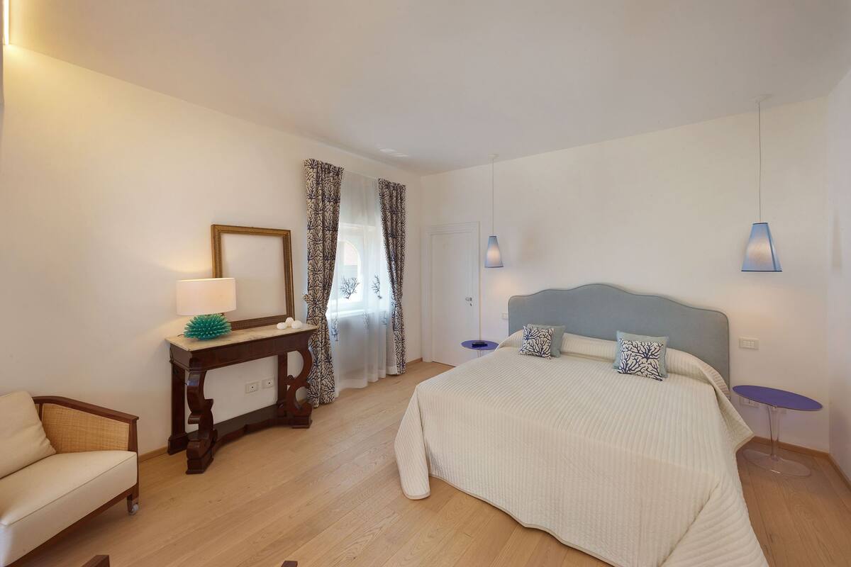 A bedroom with a bed, bedside tables, a desk, and a chair.