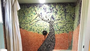 A bathroom with a mosaic wall, a toilet, and a shower area. - Mulberry Hill (Fallbrook)
