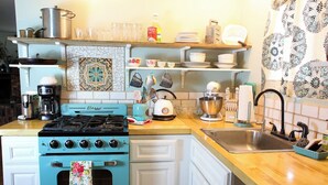 A kitchen with a blue stove, white cabinets, and a wooden countertop. - Mulberry Hill (Fallbrook)