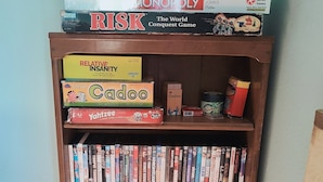 A bookshelf with various board games and books. - Mulberry Hill (Fallbrook)